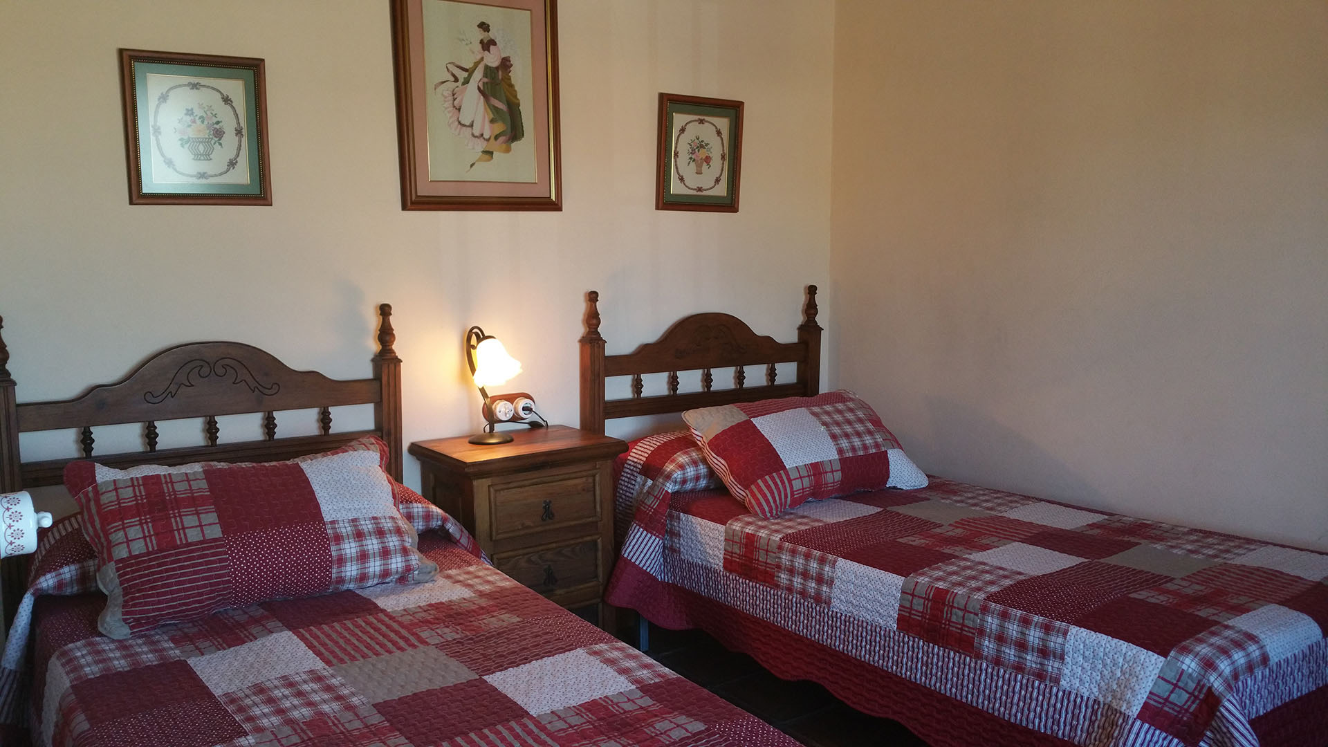 Un dormitorio con dos camas individuales y una mesitas de noche con lamparita. Decoración rusticas de madera.