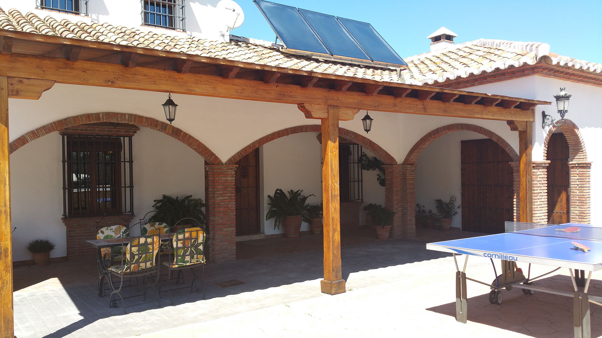 Porche de la casa rural con techado de tejas sujeto por columnas y arcos de estilo andaluz