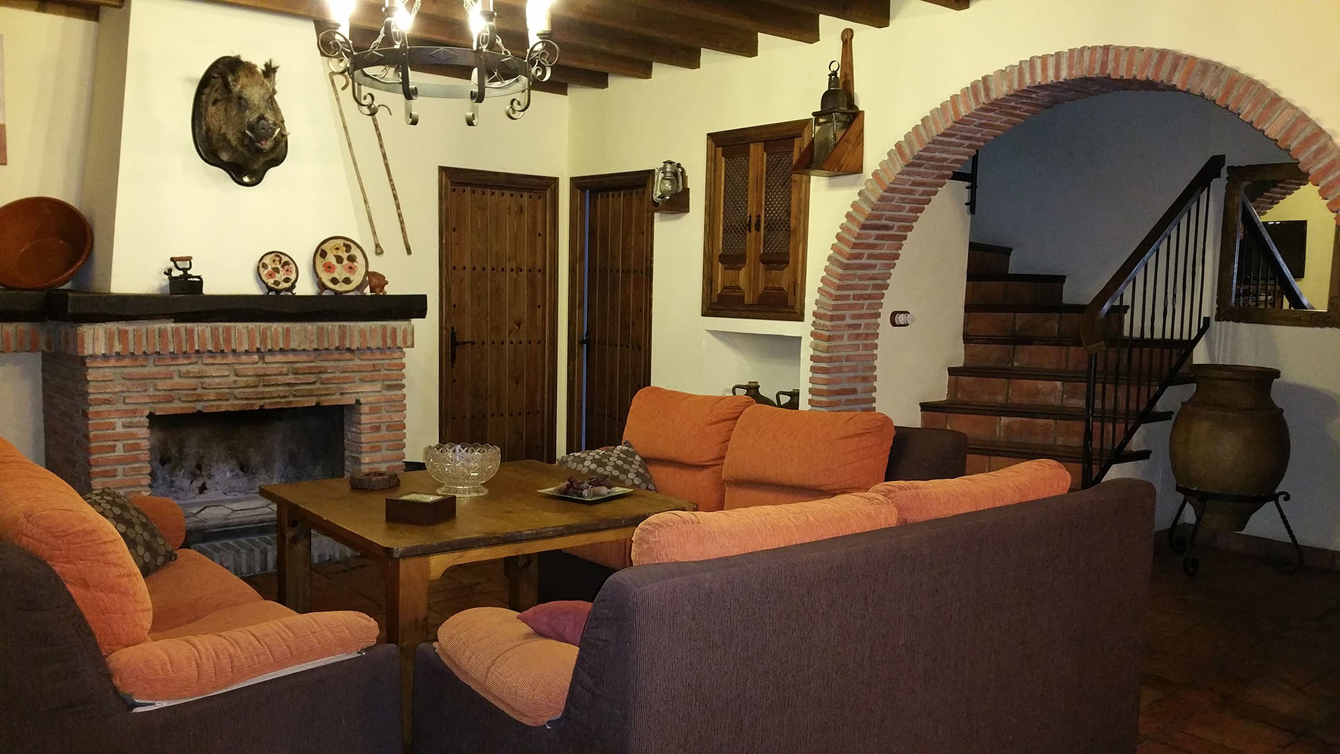 salón con decoración rustica con chimenea al fondo y zona de relax con sofá.
